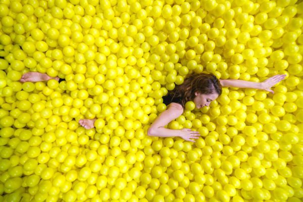 Woman Swimming Through Yellow Ball Pool